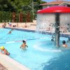Piscina all'aperto con fontana a forma di fungo e bambini che giocano.