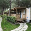 Una casa mobile con veranda in un campeggio alberato.