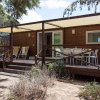 Veranda con sedie e tavolo di fronte a una casa di legno.
