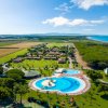 Resort con piscine azzurre contornate da prati e vista mare.