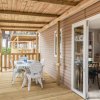 Terrazza con tavolo e sedie bianche, collegata a un interno tramite porta a vetri.