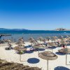 Spiaggia sabbiosa con ombrelloni e molo sullo sfondo.