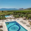 Piscina con lettini, vista su un paesaggio collinare e il mare in lontananza.