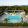 Vista dall'alto di una piscina circondata da sedie a sdraio e palme.