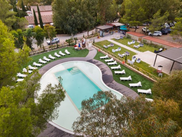 Piscina con lettini, alberi circostanti e una terrazza.