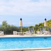 Una piscina all'aperto con sedie a sdraio e ombrelloni gialli, con colline verdi sullo sfondo.