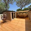 Una terrazza in legno con poltrona sospesa e tavolo da pranzo sotto il pergolato.