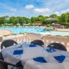 Tavolo apparecchiato vicino a una piscina con sedie e ombrelloni.